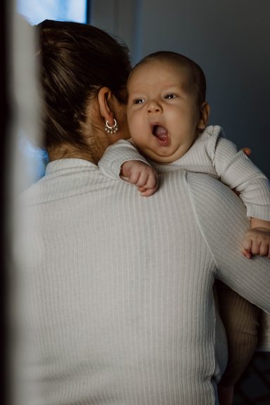 Baby-Fotoshooting: Baby gähnt auf Schulter der Mama