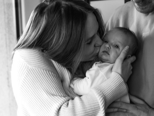 Mutter küsst ihr Neugeborenes beim Newborn Fotoshooting in Berlin - schwarzweiß